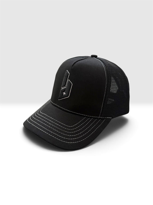 A black trucker-style baseball cap with a structured front panel, black mesh back, and white contrast stitching, featuring a stylized white logo on the front.