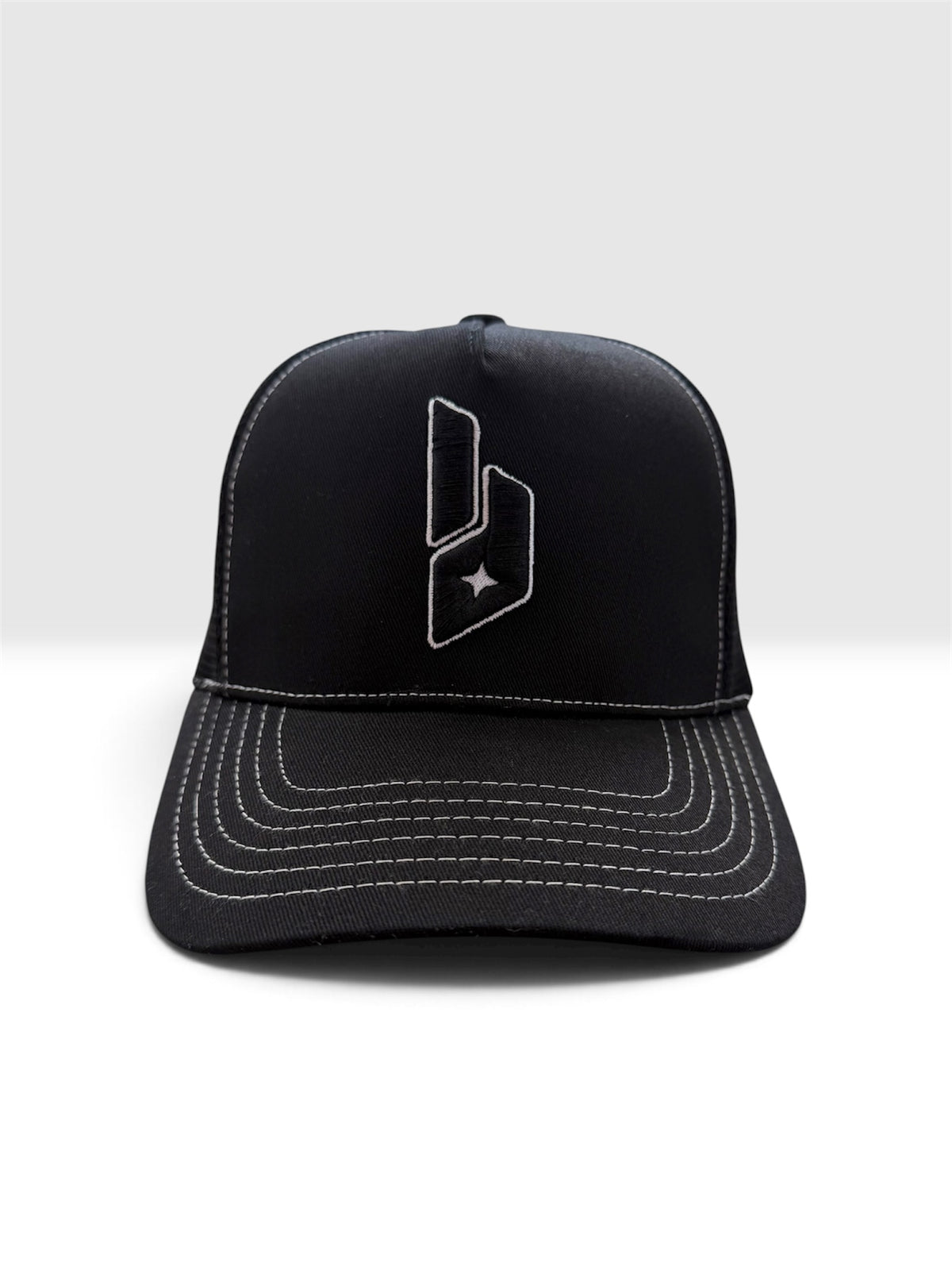 A black baseball cap with white contrast stitching and a white embroidered geometric logo on the front, shown against a light gray studio background.